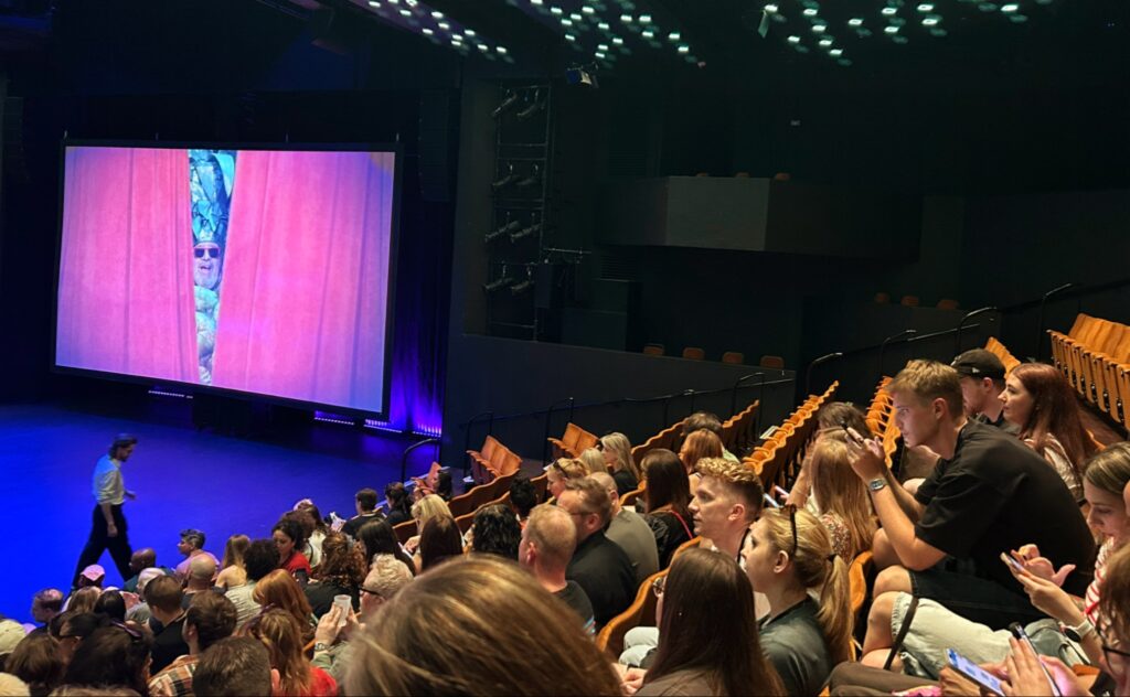 جمهور متحمس يشاهد عرض فيلم Still Pushing Pineapples في مسرح Crucible Theatre خلال مهرجان Sheffield DocFest 2025.
