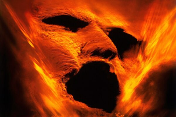 صورة تعكس وجه المومياء المغطى باللهب والدخان، مع ملامح مظلمة وفم مفتوح يعبر عن الرعب، مستوحاة من فيلم The Mummy 2026 بإخراج لي كرونين Lee Cronin.