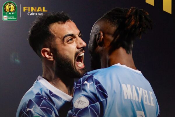 بيراميدز إف سي يهزم ماميلودي صن داونز ويتوج بلقب دوري أبطال أفريقيا لأول مرة بفضل تألق فيستون ماييليPyramids FC Defeats Mamelodi Sundowns to Win CAF Champions League for the First Time Thanks to Fiston Mayele’s Brilliance صورة تحتفي بتتويج نادي بيراميدز إف سي بلقب دوري أبطال أفريقيا. تظهر مجموعة من اللاعبين يرتدون قمصان الفريق الزرقاء والبيضاء، مع خلفية ذهبية تحمل شعار الاتحاد الأفريقي لكرة القدم (CAF) وكلمة "CHAMPIONS" باللغة الإنجليزية. اللاعبون يظهرون بتعابير فرح واحتفال.