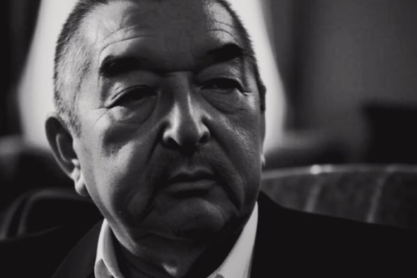 صورة تخيلية بالأبيض والأسود تظهر غراهام غرين وهو يرتدي بدلة رسمية سوداء مع ربطة عنق، يجلس في أجواء سينمائية تعكس إرثه في هوليوود.