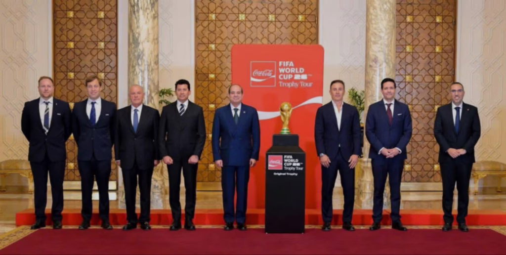 لقطة رسمية تظهر فخامة الرئيس عبد الفتاح السيسي واقفاً بجوار النسخة الأصلية لكأس العالم، وذلك خلال فعاليات استقبال السيسي لوفد الفيفا في القاهرة لدعم الملف الرياضي المصري.