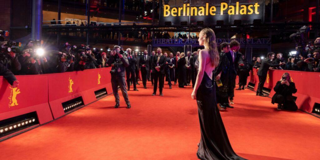 سيدة بفستان سهرة تقف على السجادة الحمراء أمام قصر Berlinale Palast وسط عدسات المصورين في مهرجان برلين.