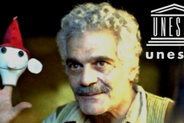 لقطة للفنان عمر الشريف يمسك بعروسة الأراجوز بيده بجانب شعار منظمة اليونسكو UNESCO.