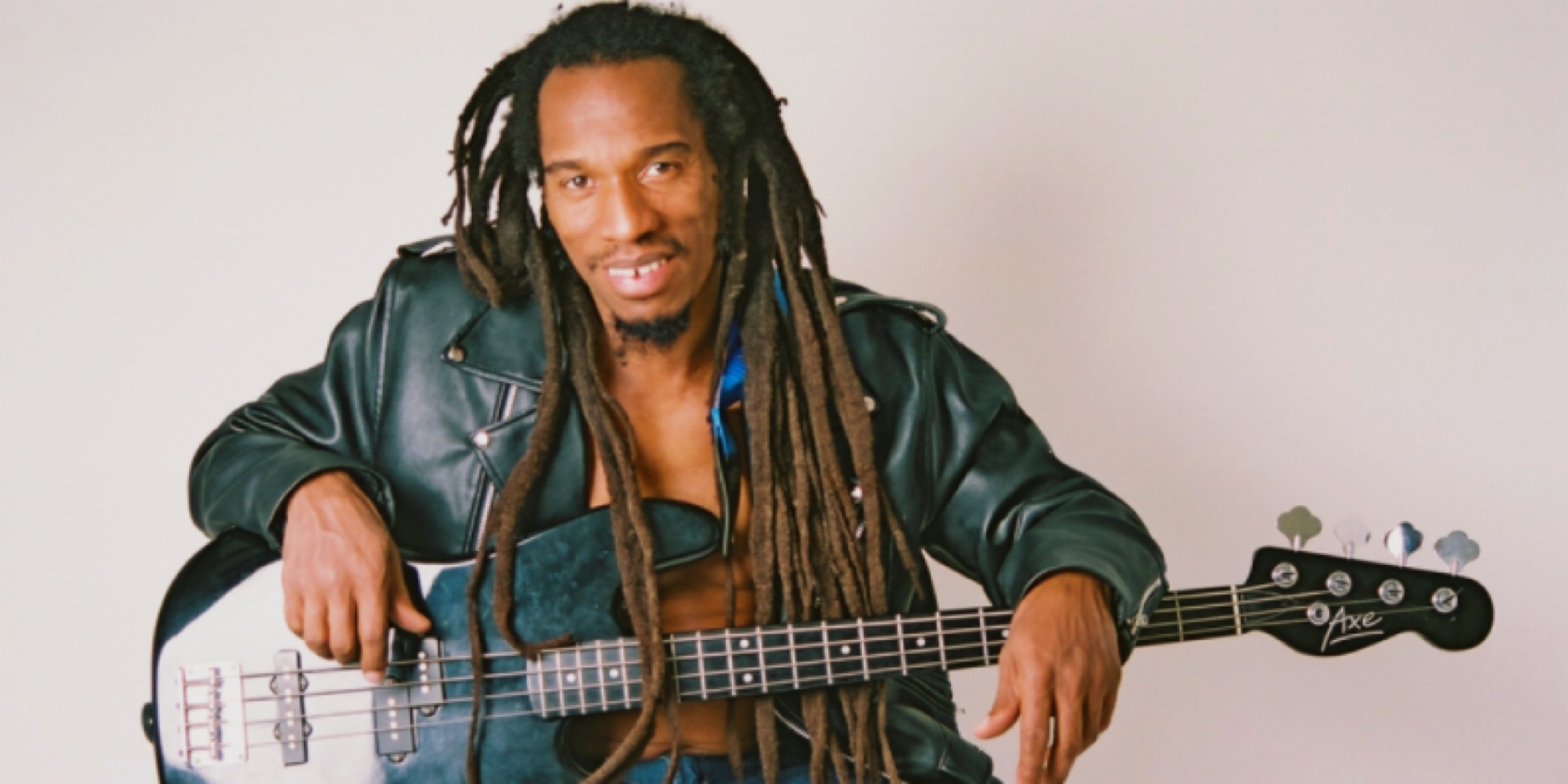 لقطة لبنيامين صفنيا، الشاعر والموسيقي البريطاني ذو شعر جديلة طويل (dreadlocks)، يجلس ويرتدي سترة جلدية سوداء، ممسكاً بغيتار باس أسود على خلفية بيضاء.