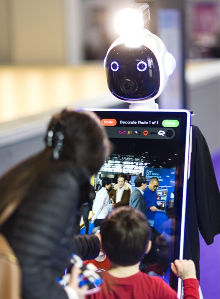 طفل يتفاعل مع روبوت اجتماعي ذكي مزود بشاشة تفاعلية لالتقاط وتزيين الصور في معرض جنيف الدولي للاختراعات.