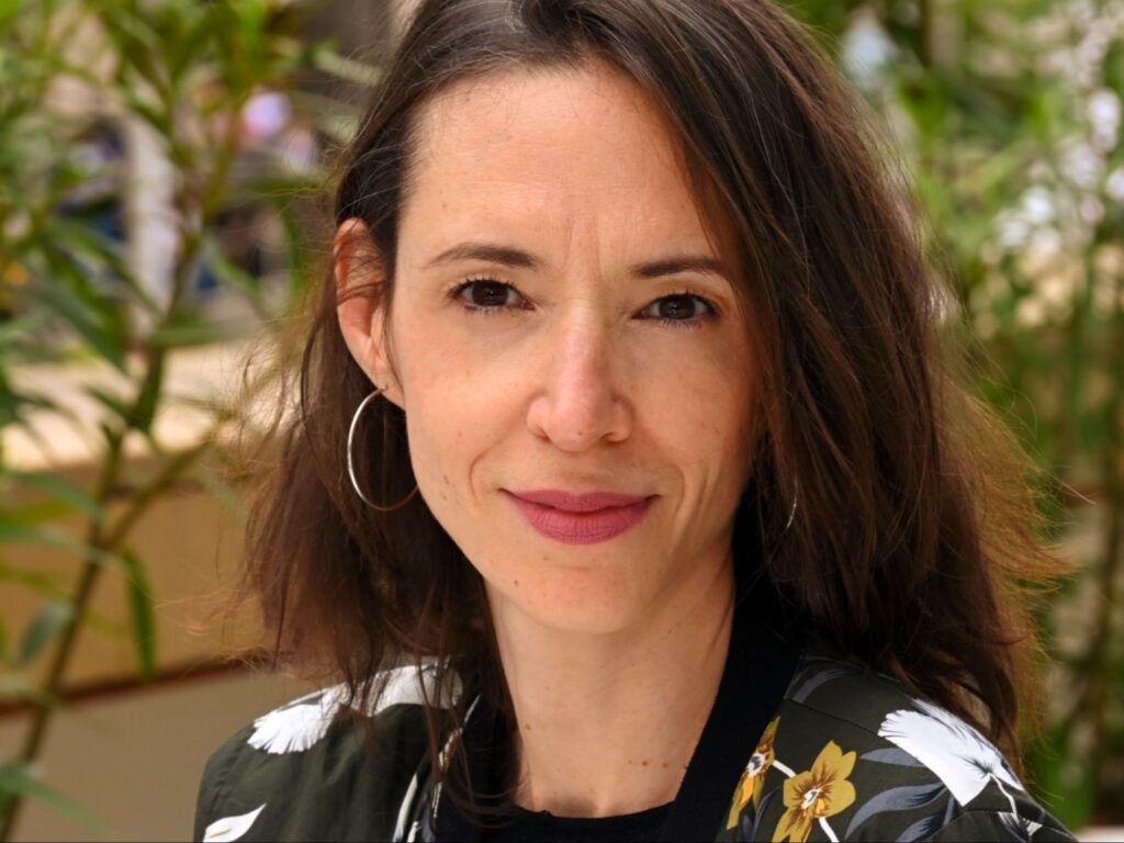 بورتريه مقرب لـ Florence Girot، مديرة المهرجانات في الاتحاد الدولي لجمعيات منتجي الأفلام (FIAPF)، تظهر بابتسامة هادئة وشعر بني منسدل.