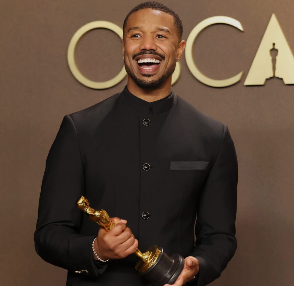 النجم Michael B. Jordan يبتسم وهو يحمل تمثال الأوسكار الذهبي بعد فوزه بجائزة أفضل ممثل في حفل جوائز الأوسكار 2026.