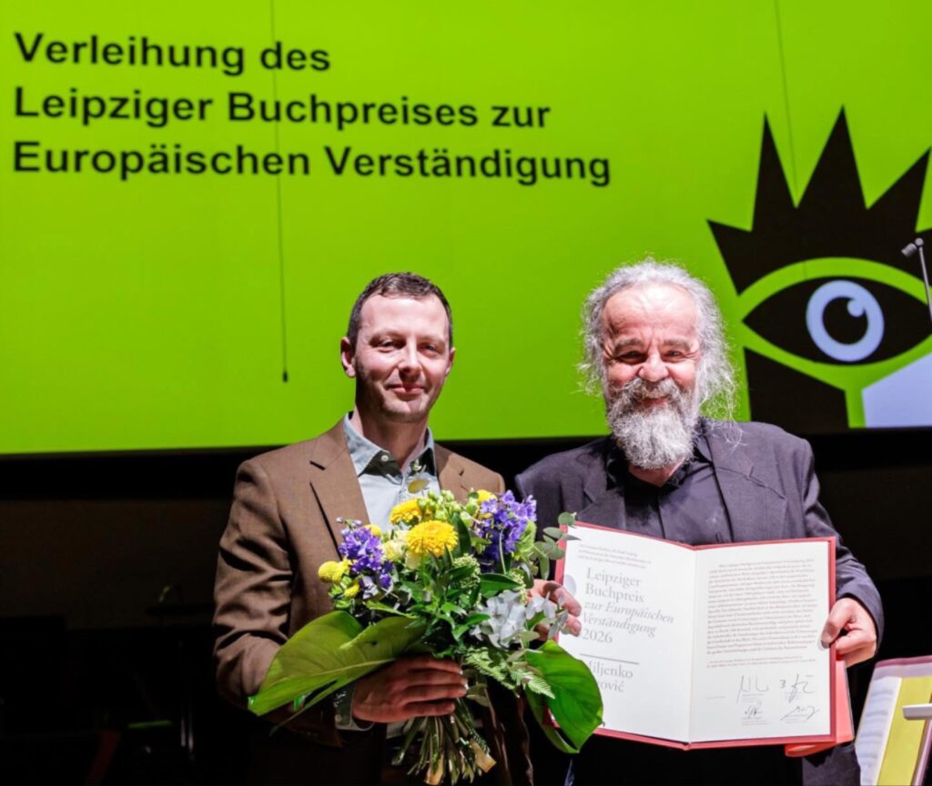 الكاتب Miljenko Jergović يبتسم حاملاً وثيقة جائزة التفاهم الأوروبي لعام 2026، وهي إحدى أبرز جوائز الأدب التي يتم توزيعها مع انطلاق معرض لايبزيغ للكتاب اليوم.
