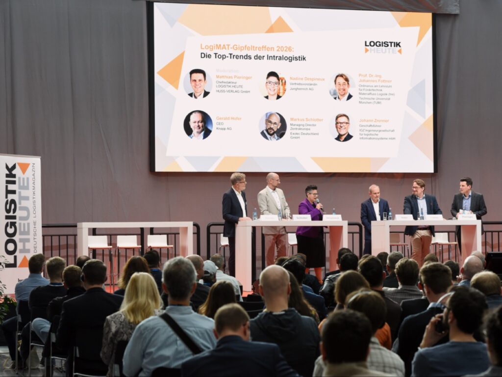 مجموعة من المتحدثين على خشبة المسرح في لوحة نقاش بمؤتمر، مع جمهور وشاشة عرض.