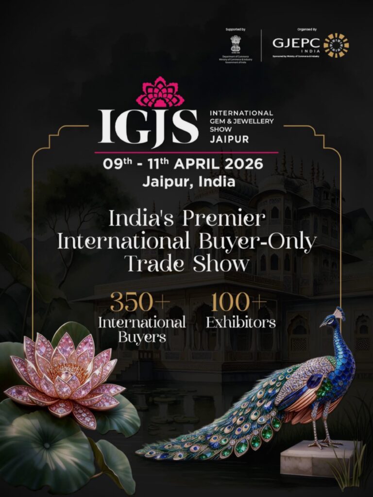 ملصق ترويجي لمعرض IGJS (معرض الجواهر والمجوهرات الدولي) في جايبور، الهند، من 9 إلى 11 أبريل 2026. يصف المعرض بأنه "معرض تجاري دولي حصري للمشترين في الهند"، مع إبراز أرقام المتوقعين: أكثر من 350 مشتراً دولياً وأكثر من 100 عارض. يشتمل على عناصر فنية لمجوهرات فاخرة: زهرة لوتس مرصعة بالمجوهرات الوردية وتمثال طاووس مرصع بالمجوهرات الملونة على خلفية قصر هندي كلاسيكي. يتضمن شعارات التنظيم والدعم من GJEPC ودائرة التجارة.