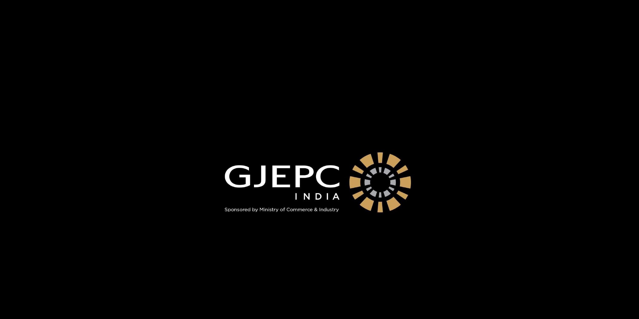 شعار مجلس تعزيز تصدير الأحجار الكريمة والمجوهرات (GJEPC INDIA) باللون الأبيض، ترافقه أيقونة دائرية هندسية باللونين الذهبي والرمادي ترمز للقطاع، مع نص في الأسفل يشير إلى رعاية وزارة التجارة والصناعة الهندية، الكل يظهر بوضوح على خلفية سوداء صماء.
