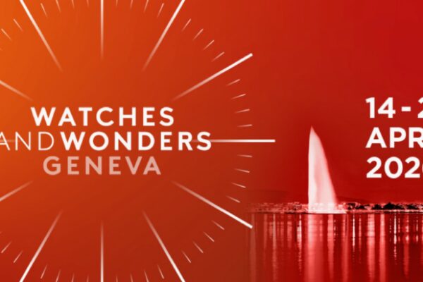 شعار رسومي لمعرض "WATCHES AND WONDERS GENEVA" (النص باللون الأبيض) على خلفية حمراء متدرجة. يتميز الجزء الأيسر بقرص ساعة مجرد ونمط شعاعي. ويظهر الجزء الأيمن التواريخ "14 - 20 APRIL 2026" بجوار صورة لأفق جنيف الليلي المضاءة مع نافورة Jet d'Eau الشهيرة.
