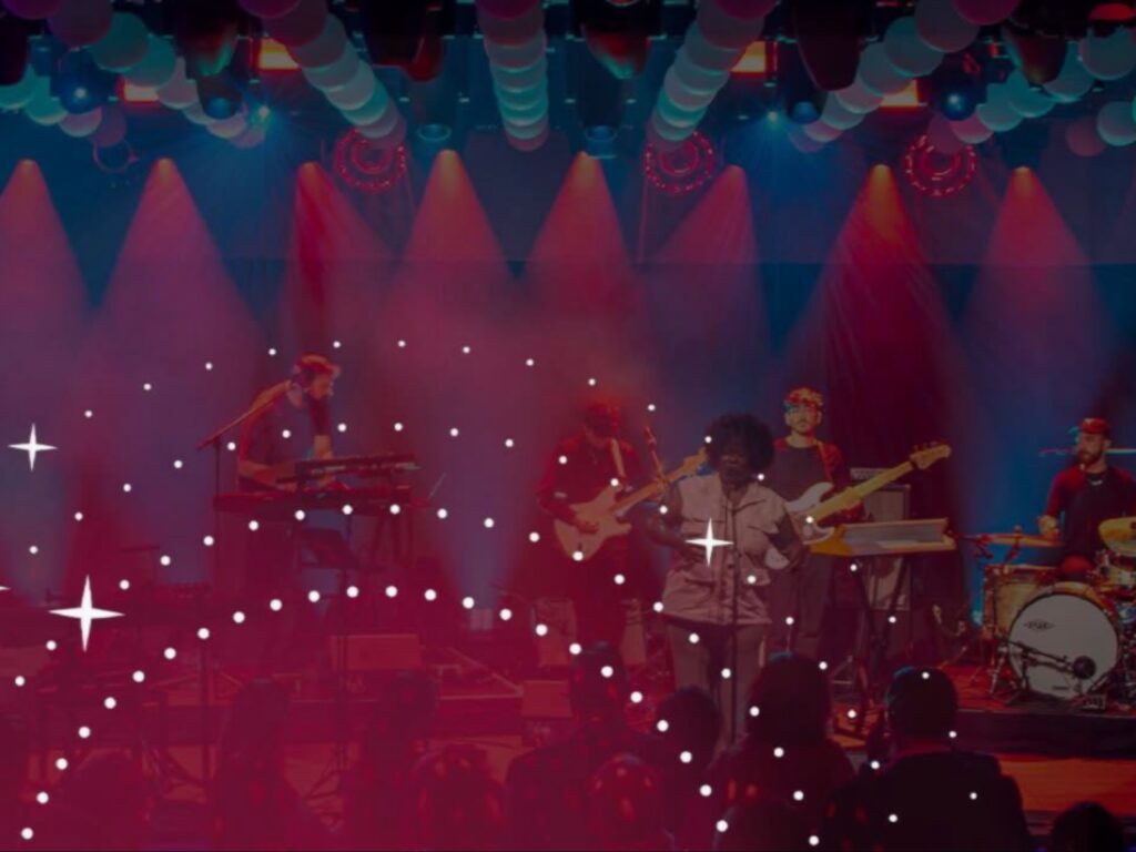 صورة فوتوغرافية لفرقة موسيقية تقدم عرضاً حيّاً على خشبة مسرح ذات إضاءة حمراء وزرقاء خافتة، مغطاة بفلتر أحمر مزخرف، وذلك ضمن الأنشطة الفنية والثقافية لحدث معرض Watches and Wonders Geneva بالتعاون مع مهرجان مونترو جاز.