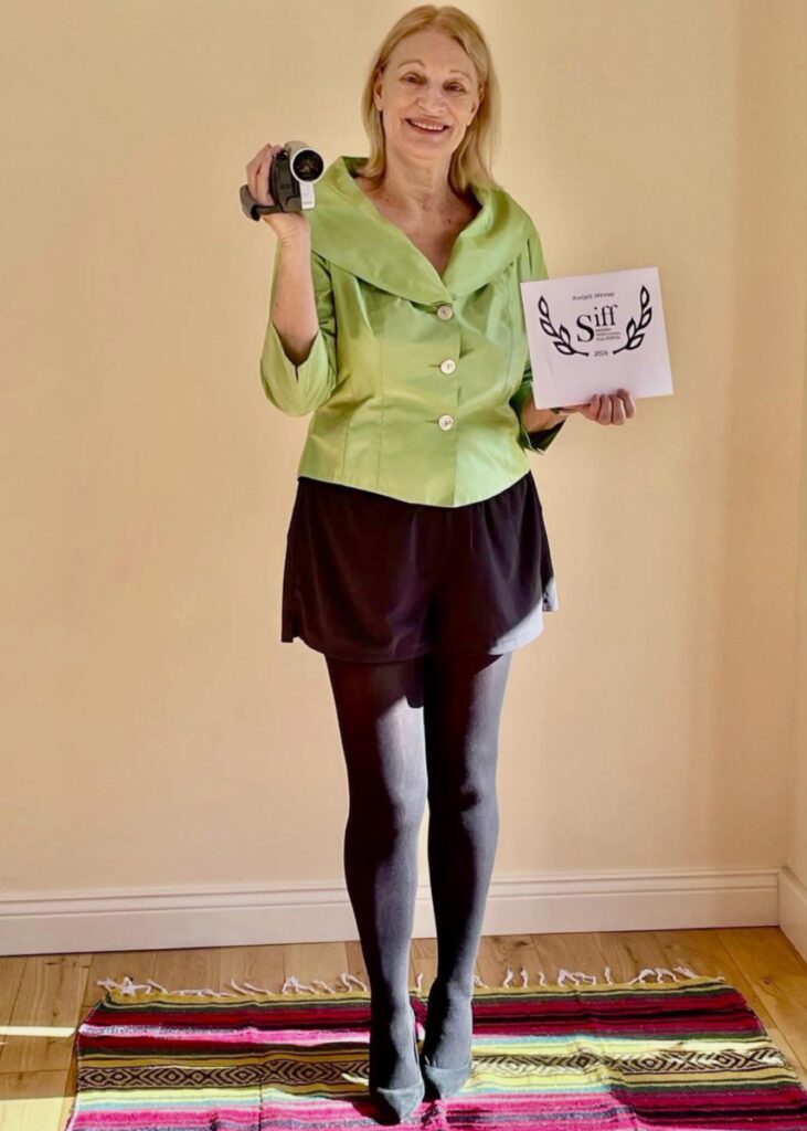 المخرجة Ingrid Nachstern تحمل كاميرا فيديو وشهادة فوز بجائزة SIFF من مهرجان Swedish International Film Festival.