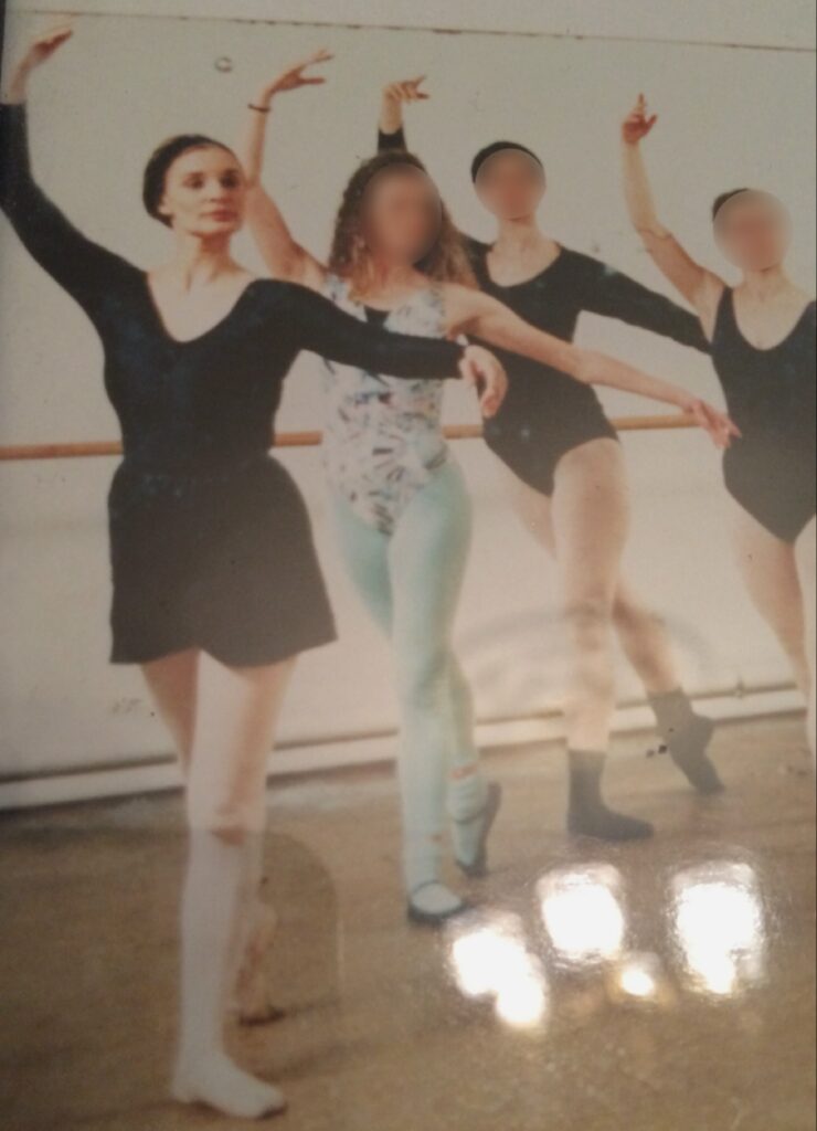 مجموعة من الراقصات في استوديو باليه يؤدين حركات رقص كلاسيكية؛ تبرز في المقدمة راقصة ترتدي تنورة سوداء وجوارب بيضاء، مع وجود راقصات أخريات في الخلفية بوجوه غير واضحة.