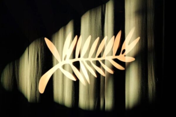 شعار سعفة ذهبية مضاءة بوضوح على خلفية من ستائر مخملية داكنة، ترمز لافتتاح فعاليات مهرجان كان السينمائي الدولي 2026.