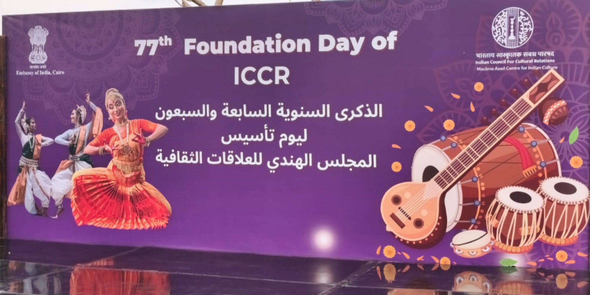 لافتة أرجوانية كبيرة بمناسبة الذكرى السابعة والسبعين لتأسيس المجلس الهندي للعلاقات الثقافية ضمن احتفالية ICCR بالقاهرة. يبرز التصميم ثلاث راقصات بالزي الهندي التقليدي وآلات موسيقية عريقة مثل "الفينا" وطبلة "التابلا"، مع شعارات سفارة الهند بالقاهرة ومركز مولانا آزاد الثقافي.