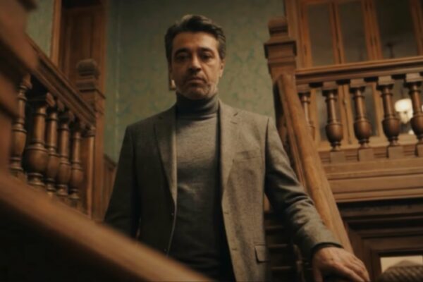 الفنان عصام كمال يقف على درج خشبي في مشهد من كليب أغنية ويعني لو.