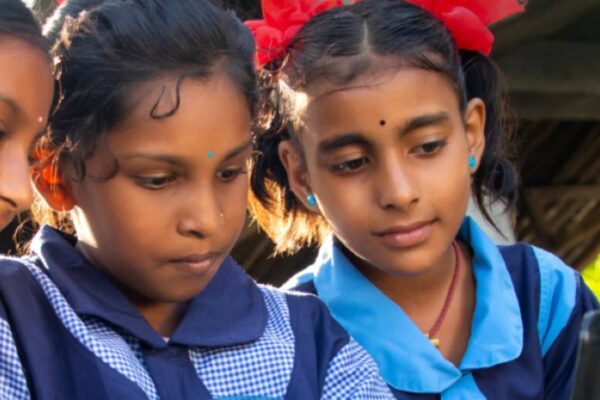 لقطة تعبيرية لطفلين يستخدمان جهازاً لوحياً مع تراكيب بصرية للعقل الرقمي، ترمز لابتكارات التعليم المدعومة من جائزة اليونسكو لتكنولوجيا المعلومات 2026.