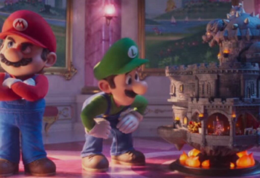 لقطة من فيلم سوبر ماريو جالاكسي تظهر ماريو واقفاً بوضعية حازمة ولويجي ينظر بفضول إلى مجسم لقلعة حجرية طائرة فوق كرات نارية، داخل قاعة فخمة.