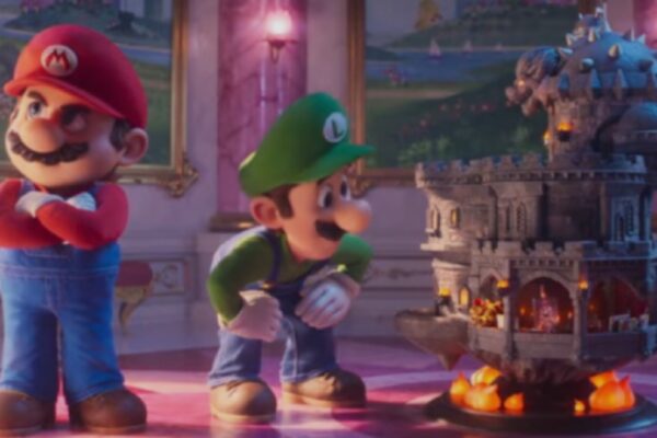 لقطة من فيلم سوبر ماريو جالاكسي تظهر ماريو واقفاً بوضعية حازمة ولويجي ينظر بفضول إلى مجسم لقلعة حجرية طائرة فوق كرات نارية، داخل قاعة فخمة.