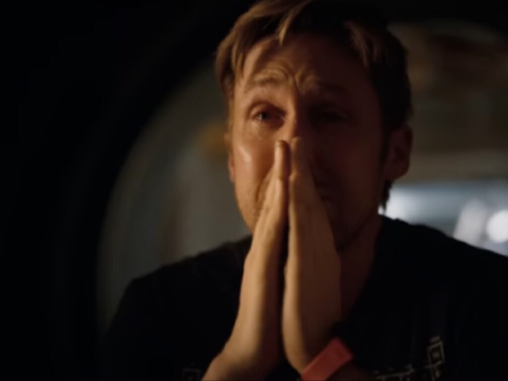 لقطة مقربة للممثل رايان غوسلينغ في بيئة مظلمة، يظهر بتعبيرات وجه مؤثرة واضعاً يديه أمام وجهه في وضعية تضرع، من فيلم مشروع هيل ماري.