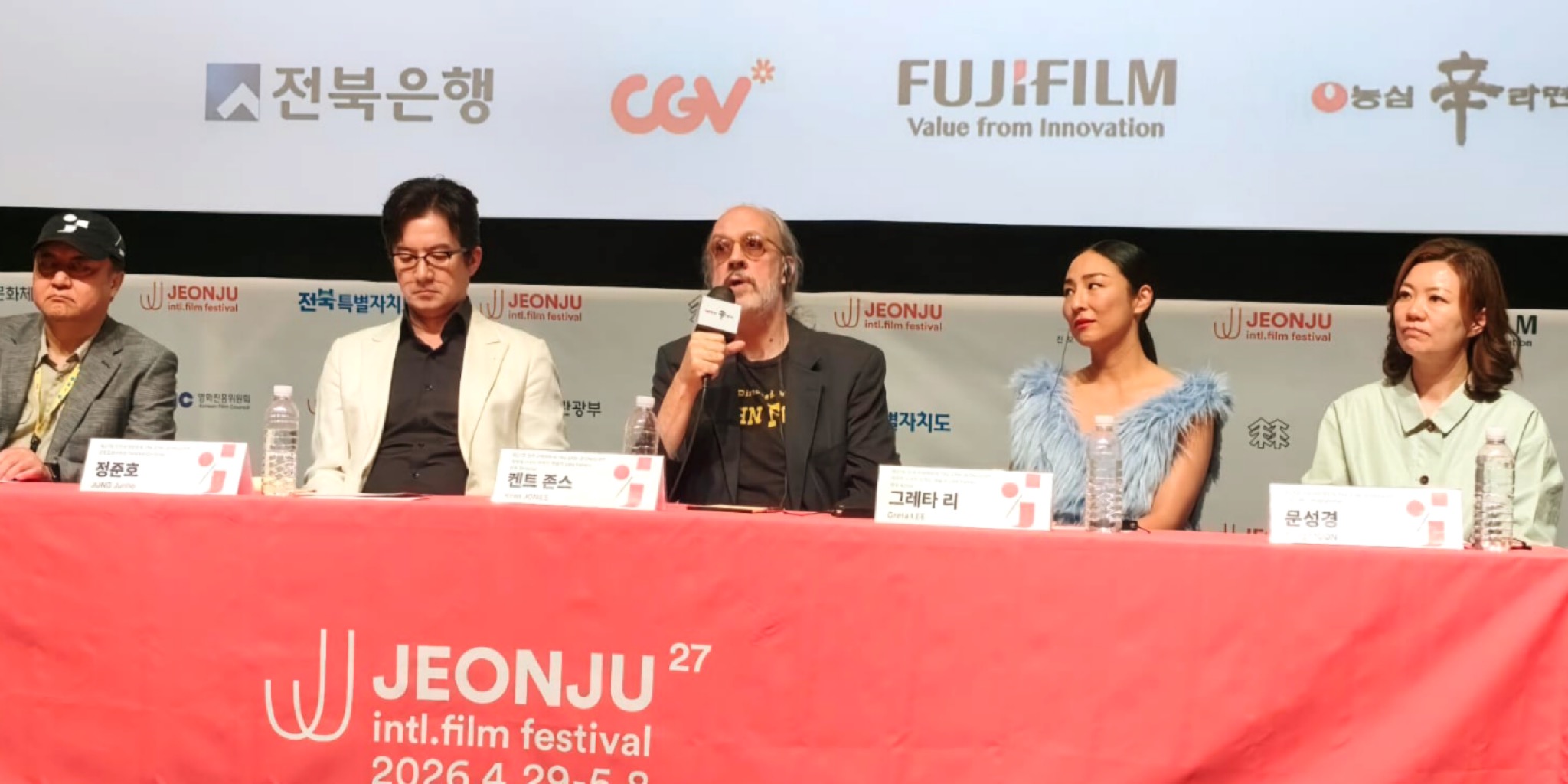 المخرج كينت جونز يتحدث في المؤتمر الصحفي لفيلم شهرة متأخرة وإلى جواره النجمة غريتا لي والمدير المشترك للمهرجان جونغ جونهو والمبرمجة سونغ مون في مهرجان جونجو.
