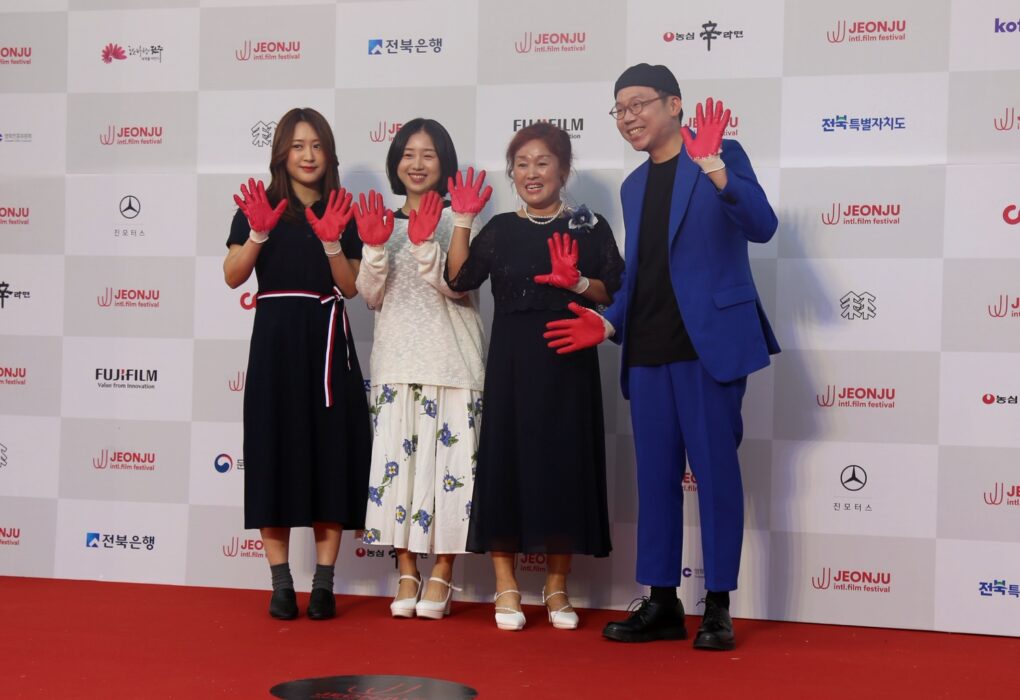 لقطات مجمعة تظهر السجادة الحمراء ومَراسم المنصة الرئيسية مع شاشات العرض الكبيرة التي تحمل شعار المهرجان بحضور الجمهور في حفل افتتاح مهرجان جونجو السينمائي الدولي.