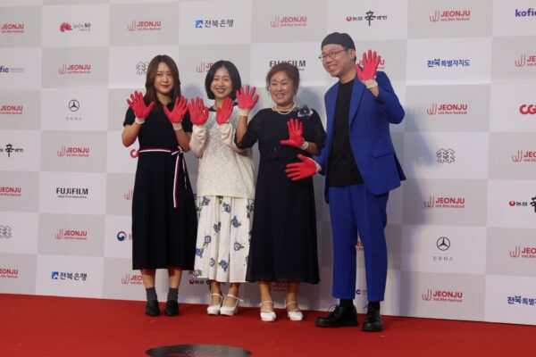 لقطات مجمعة تظهر السجادة الحمراء ومَراسم المنصة الرئيسية مع شاشات العرض الكبيرة التي تحمل شعار المهرجان بحضور الجمهور في حفل افتتاح مهرجان جونجو السينمائي الدولي.