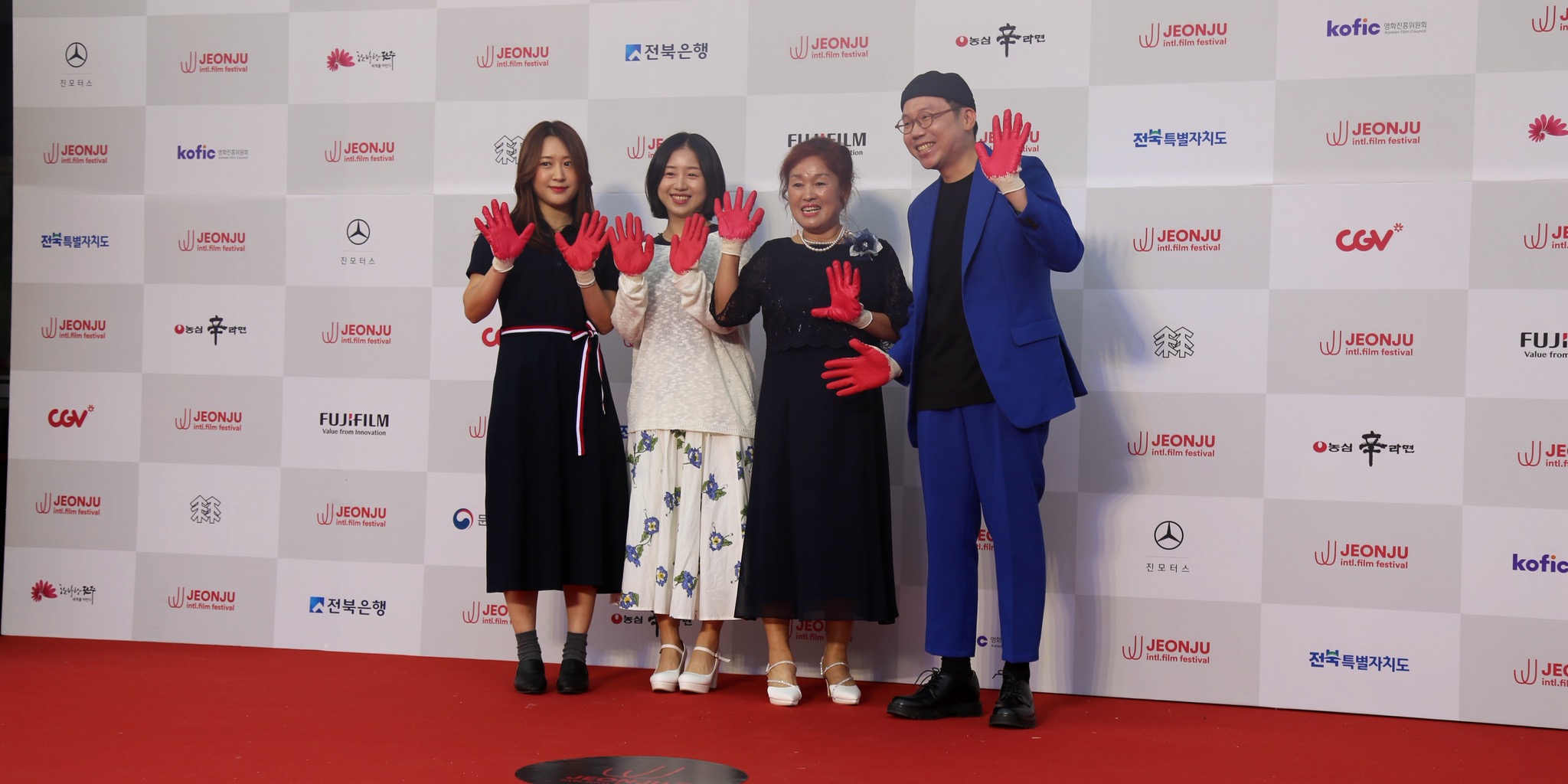 لقطات مجمعة تظهر السجادة الحمراء ومَراسم المنصة الرئيسية مع شاشات العرض الكبيرة التي تحمل شعار المهرجان بحضور الجمهور في حفل افتتاح مهرجان جونجو السينمائي الدولي.