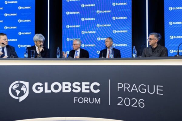 ستة متحدثين يجلسون جنباً إلى جنب خلف طاولة نقاشية عريضة كُتب عليها "GLOBSEC FORUM PRAGUE 2026"، وخلفهم شاشات زرقاء مزينة بشعار غلوبسيك المتكرر، أثناء إحدى الجلسات الحوارية في المؤتمر