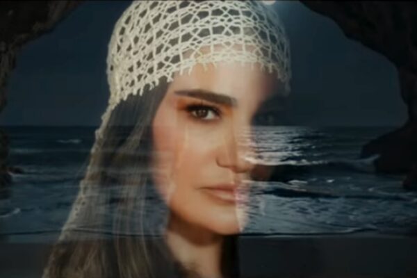 صورة بورتريه بتقنية العرض المزدوج لوجه ديريا بيداڤاجي متداخلاً مع مشهد لأمواج البحر وكهف ليلي، تجسيداً لحالة الشجن في أغنية Atlatırım
