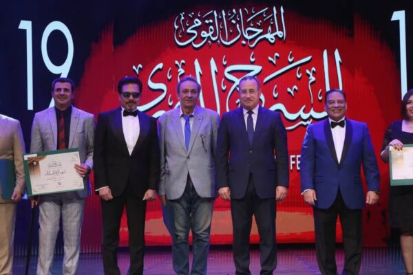 وزير الثقافة ورئيس المهرجان القومي للمسرح المصري يتوسطان عدداً من المكرمين على خشبة المسرح خلال حفل افتتاح الدورة التاسعة عشرة