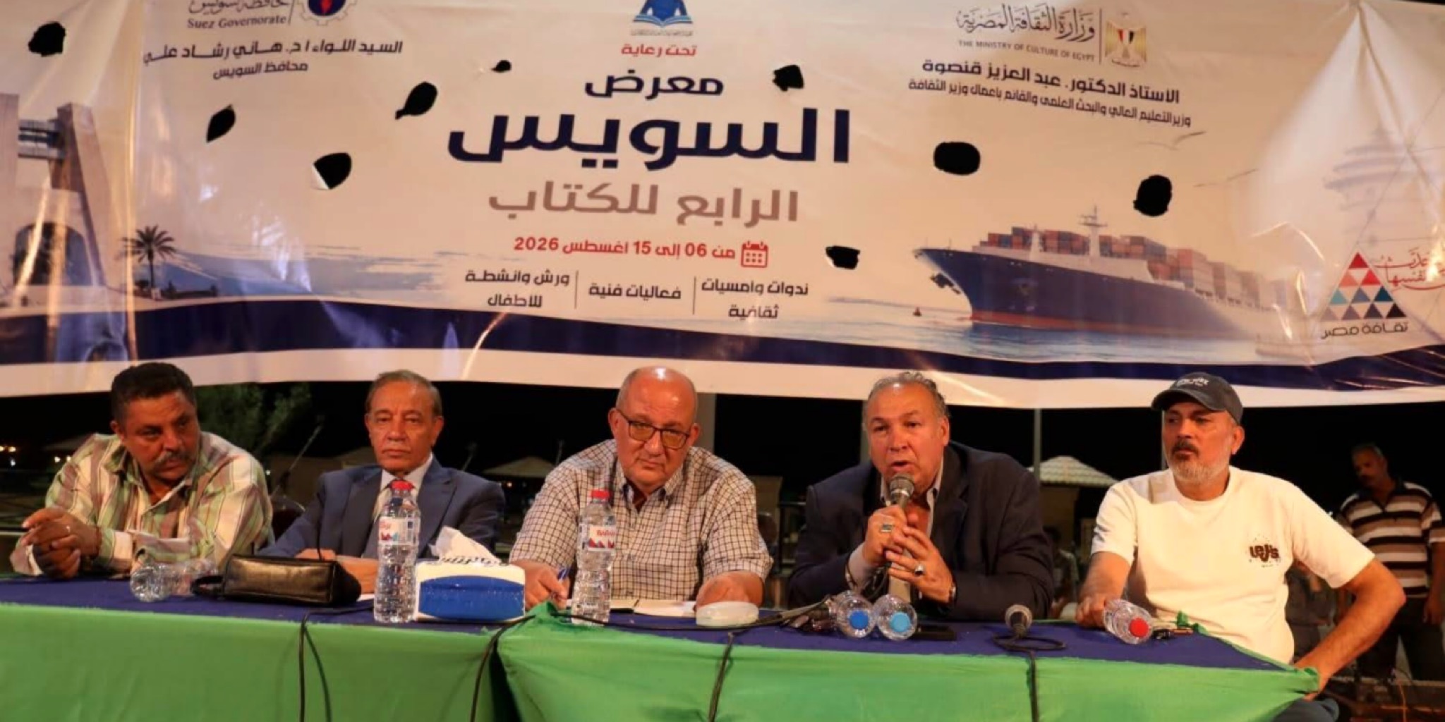 خمسة متحدثين على منصة ندوة نقاشية حول تراث السمسمية وخلفهم لافتة توضح فعاليات معرض السويس الرابع للكتاب