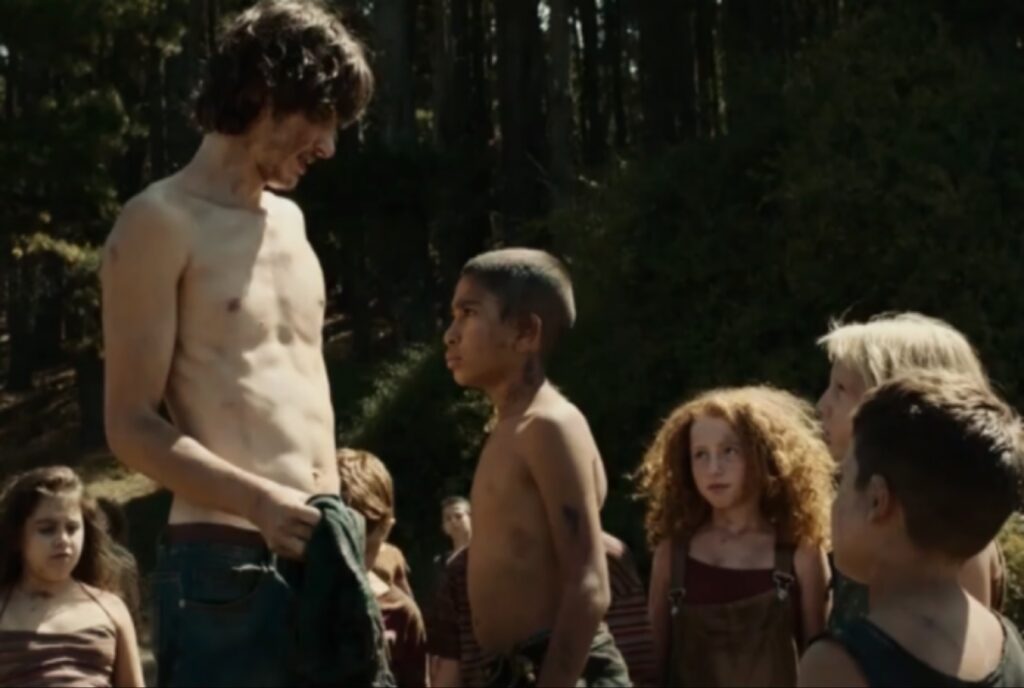 الممثل Romeo Perrone يتحدث مع طفل وسط مجموعة من الأطفال في الغابة في فيلم Alberi erranti