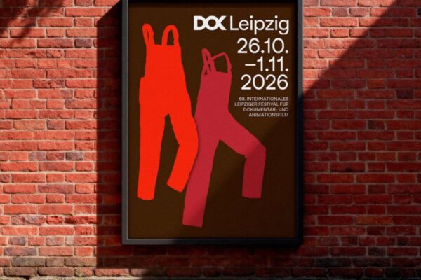 الملصق الدعائي لفعاليات مهرجان دوك لايبزيغ 2026 معلق على جدار من الطوب، ويتميز بتصميم يضم زي العمال باللونين الأحمر والبرتقالي