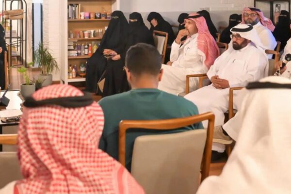 صورة لجانب من الحضور في أمسية أوراق سردية داخل مقهى كولتشر، يظهر فيها رجال بالزي السعودي التقليدي ونساء بالعباءات السوداء يجلسون للاستماع والمشاركة باهتمام، بينما يتحدث أحد الحضور عبر الميكروفون